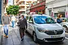 Hvit drosje i Las Palmas på Gran Canaria står parkert i en smal bygate med fotgjengere rundt.